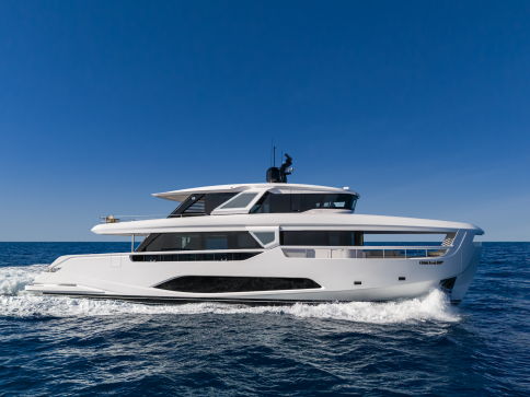 A modern white luxury yacht cruises on calm blue ocean water under a clear sky.
