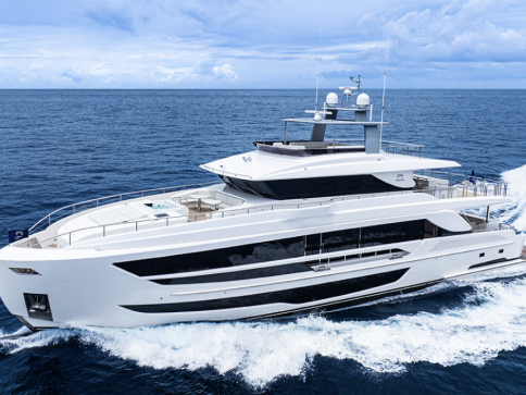 A modern white luxury yacht cruises swiftly on deep blue ocean waters under a partly cloudy sky, creating waves as it moves.