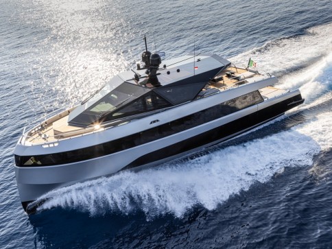 A modern white luxury yacht cruises swiftly across the blue sea, creating a trail of white foam in its wake under bright sunlight.