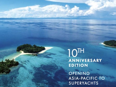 Aerial view of small, lush islands surrounded by clear blue ocean under a cloudy sky, with text reading 10th Anniversary Edition: Opening Asia-Pacific to Superyachts.