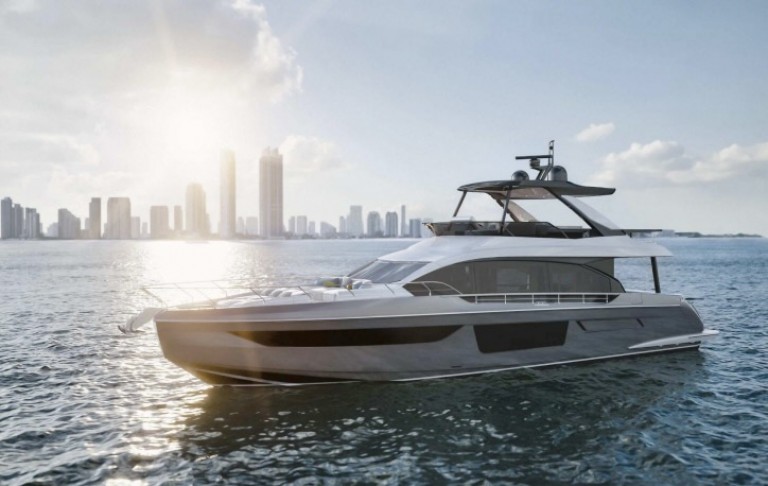 A modern luxury yacht floats on calm blue water with a city skyline and tall buildings in the background under a bright, sunny sky.
