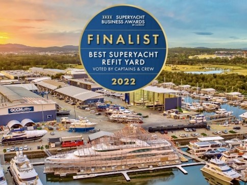 Aerial view of a marina and boatyard with superyachts and buildings, featuring a large circular badge stating “2022 Superyacht Business Awards Finalist: Best Superyacht Refit Yard, Voted by Captains & Crew”.