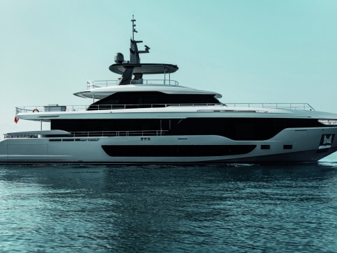 A modern white yacht with sleek black accents floats on calm blue water under a clear sky.