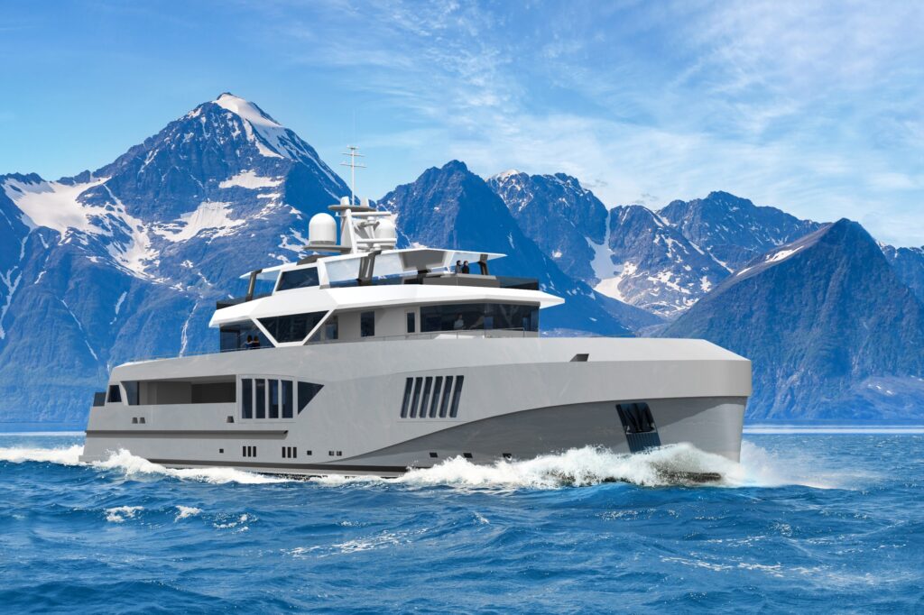 A modern luxury yacht sails through blue ocean waters with tall, snow-capped mountains in the background under a partly cloudy sky.
