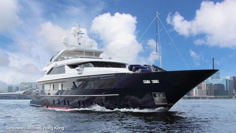 A large, modern luxury yacht cruises on calm water near a city skyline under a blue sky with scattered clouds. Text in the lower left reads Sanlorenzo 46Steel, Hong Kong.