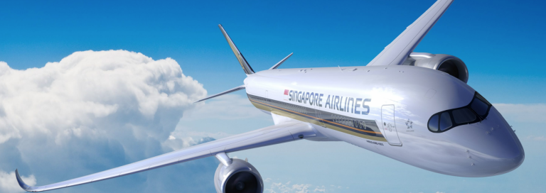 A Singapore Airlines aeroplane flies above the clouds in a bright blue sky, showing the airline’s logo and sleek design on the aircraft’s body.