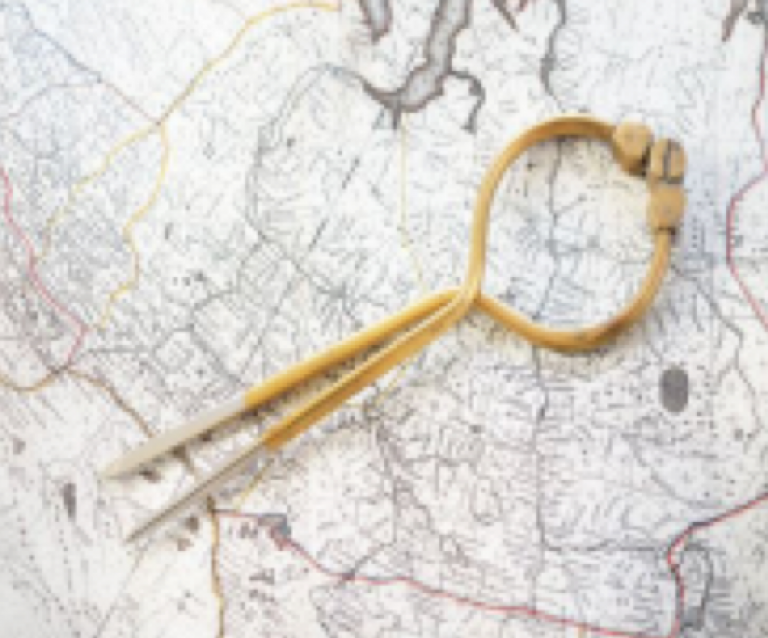 A pair of vintage callipers or dividers rests on an old, detailed map with geographical lines and markings.