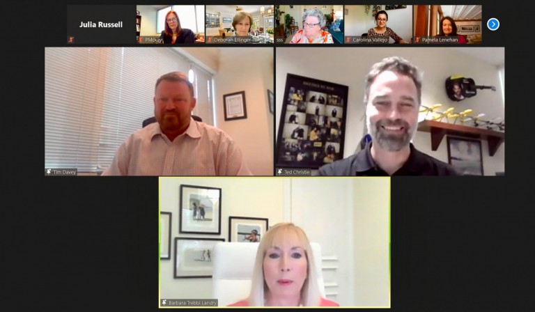 A Zoom video call with nine participants. Three people are in large video windows: a man in a white shirt, a man with a beard smiling, and a woman with blonde hair. Six others are shown in small top-row thumbnails.