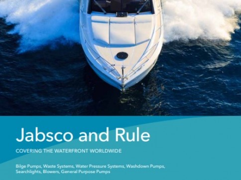 A white motorboat speeds through blue water, creating a wake. Text on a blue overlay reads Jabsco and Rule Covering the Waterfront Worldwide with a list of marine equipment products below.